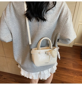 Detail of cream white leather crossbody bag with pearl cluster and lace ribbon charm