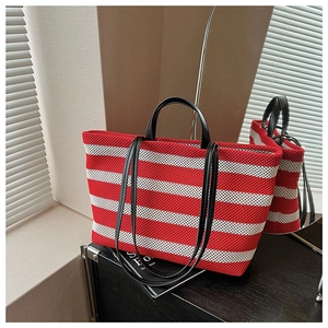 Gros plan du sac cabas tissé à rayures rouges et blanches avec poignées en cuir noir