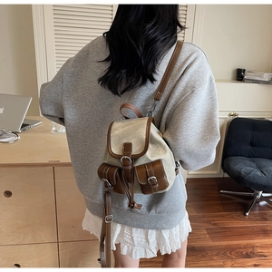 Detail of vintage canvas and leather backpack with drawstring closure worn by a model