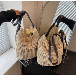 Detail of straw woven hobo bag showing brown leather strap and soft fabric lining