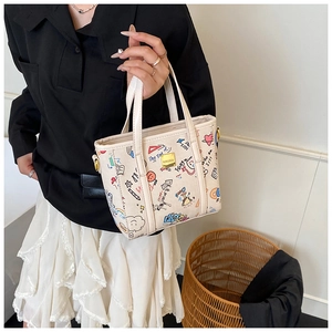 Detail view of cream handbag with colorful graffiti prints and golden metal plaque