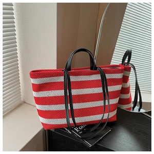 Détail du sac cabas en tricot rayé rouge et blanc avec anses noires et texture mesh
