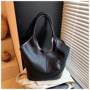Detail shot of black lychee grain tote bag showing premium leather texture and hanging charm