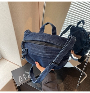 Detailed close-up of dark blue denim shoulder bag with frayed edges and retro texture