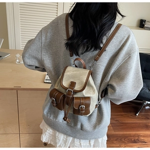 Detail view of mini plaid backpack with beige canvas and brown leather straps on a model