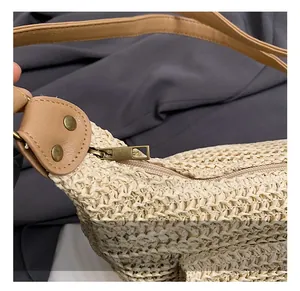 Detail of woven straw shoulder bag with brown leather strap and bronze metal hardware
