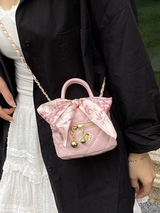 Pink quilted mini crossbody bag with gold ball chain and floral scarf accessory