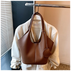 Close-up of brown lychee pattern leather tote bag with round coin purse accessory