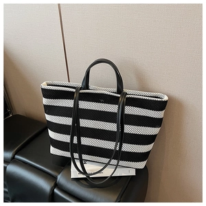 Gros plan détaillé sur la texture tricotée à rayures noires et blanches et anses en cuir du sac