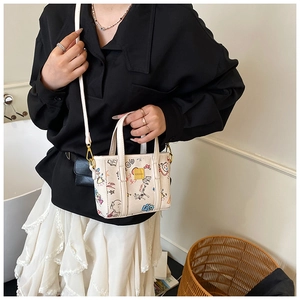 Detail of trendy bucket bag showing colorful cartoon graffiti print and gold hardware