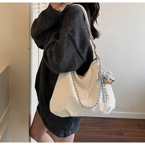 Detail of cream white hobo bag with thick silver chain and cute teddy bear charm