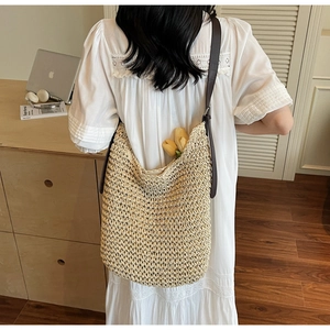 Close-up of handmade beige straw woven tote bag featuring dark brown adjustable strap
