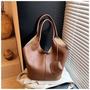 Detail of warm brown lychee grain leather tote bag with round pendant in a cozy interior