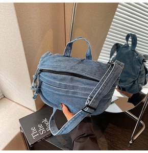 Detail of blue denim crossbody bag featuring zippered compartments and adjustable strap