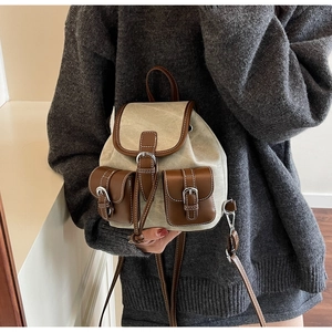 Detail of vintage canvas and brown leather backpack with front buckle pockets and flap