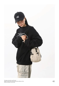 Modèle portant un petit sac bandoulière beige en nylon avec un sweat à capuche
