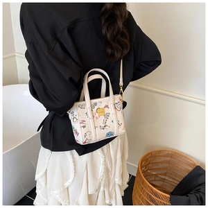 Lifestyle shot of trendy graffiti bucket bag with colorful patterns and gold hardware
