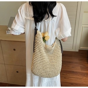 Close-up of woven straw tote bag with brown leather strap and decorative yellow tulip