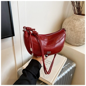 Détail du sac croissant bordeaux avec bandoulière nouée et cuir texturé ciré vintage