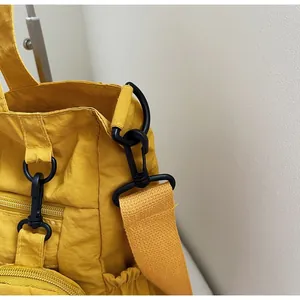 Detail of durable black hook and wide fabric strap on yellow nylon commuter tote bag