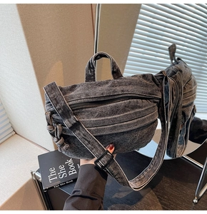 Close-up of a washed grey denim crossbody bag with adjustable strap on a wooden surface