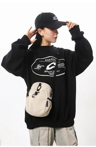 Détail d'un petit sac bandoulière en nylon blanc cassé avec cordon de serrage et logo sur noir