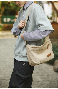Detail of water-resistant nylon messenger bag with leather logo patch and zip pockets