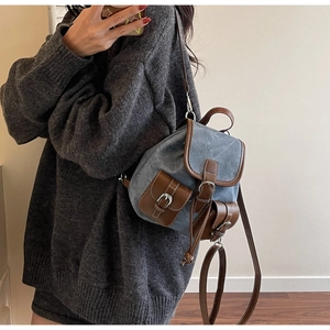 Detailed view of vintage blue denim mini backpack with brown leather trim and front pockets