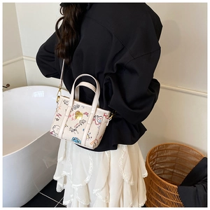 Detail of crossbody mini bag featuring colorful graffiti prints and gold hardware buckle