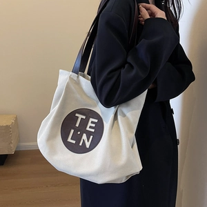 Large white canvas tote bag with brown leather handles and logo patch for daily commute