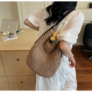 Detailed close-up of woven straw tote bag texture and high-quality brown leather straps