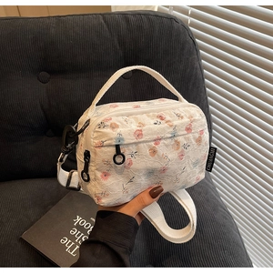 Detailed view of white lace crossbody bag with pink floral pattern and black zip pullers