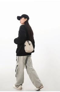 Modèle portant un sac bandoulière en nylon crème imperméable au style urbain outdoor