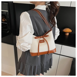 Detail of minimalist straw tote with leather bow and brand tag on a model shoulder