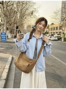 Outdoor shot of a brown large capacity nylon messenger bag with adjustable strap