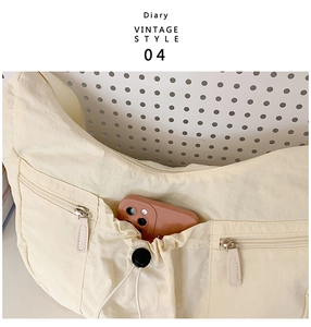 Detailansicht der großen cremefarbenen Halbmondtasche mit Taschen und Handy-Stauraum