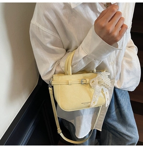 Detail der gelben Faltenleder-Eimertasche mit Spitze- und Perlenbogen-Anhängern am Riemen