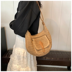 Detail of a beige straw crescent bag with brown leather pocket flap and metal studs