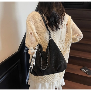 Detail of black Hobo tote bag with metallic chain and cute tassel ribbon charms