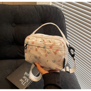 Detail of floral lace shoulder bag with dual zipper compartments and textile strap