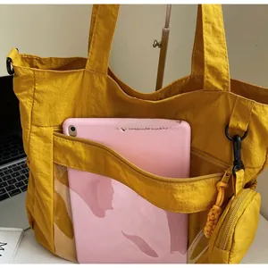 Macro shot of large yellow nylon tote bag featuring front zipper pocket and round pouch