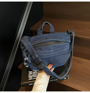Macro view of dark blue denim shoulder bag with fringe zipper pull and denim texture