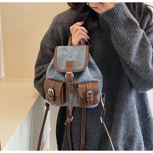 Detail of vintage mini backpack in light blue washed denim with brown leather trim and buckles
