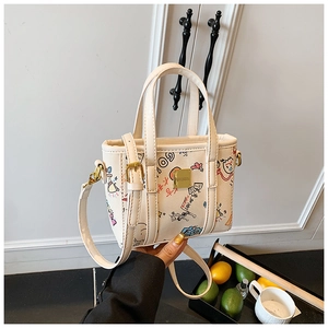 Close-up of cream leather bucket bag featuring colorful graffiti prints and gold hardware