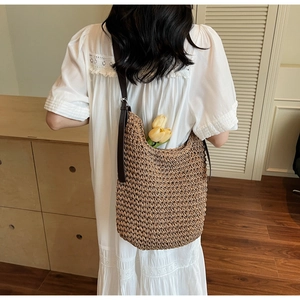 Detail of woven straw tote bag with brown leather strap and large interior capacity