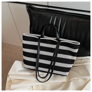 Détail d'un sac cabas en maille à rayures noires et blanches avec double poignée