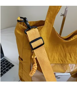 Detail of yellow nylon tote bag with wide shoulder strap and front PVC phone pocket