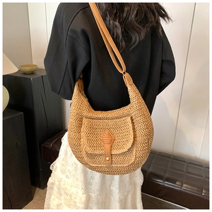 Detailed view of the woven hobo straw bag with brown leather strap on female model