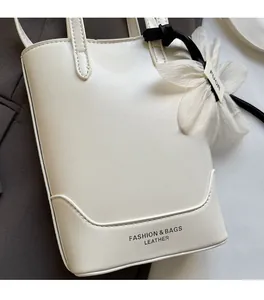 Détail d'un sac seau blanc en cuir avec texture grainée et pendentif fleur élégant