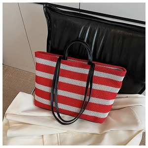 Détail du sac cabas à rayures rouges et blanches avec doubles anses en cuir noir élégant